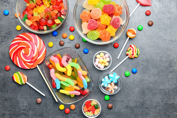 Wall Mural - Bowls with delicious candies on grey background