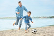 © Africa Studio - Dad and son playing football together on the beach