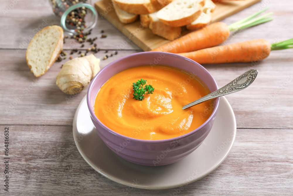 Delicious carrot soup on wooden table