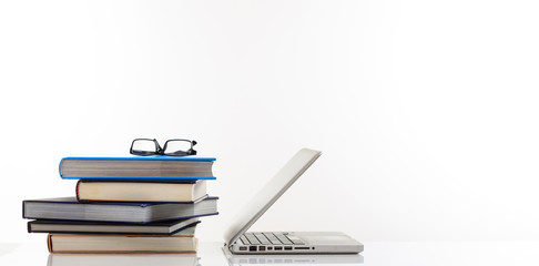 Education concept. Books stack and a laptop isolated on white background - copy space