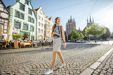 portrait of a young woman tourist traveling with photo camera in the old town of erfurt city, german