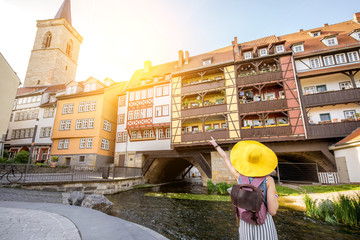 young woman tourist in yellow hat standing back on the famous merchants bridge background in erfurt 