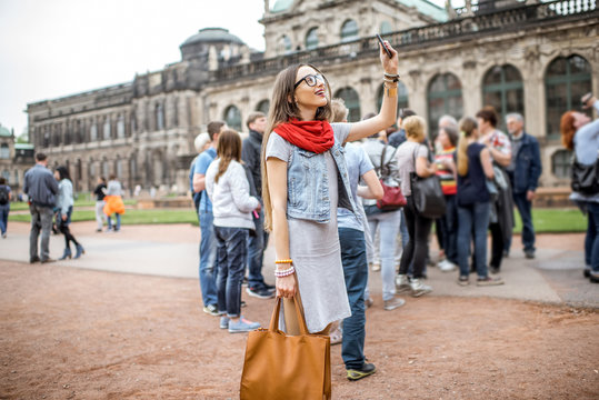 young smiling woman photographing with smartphone while visiting with tourist group the old palace i