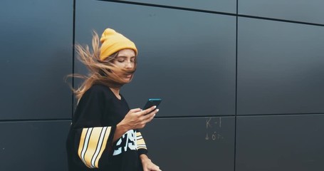 Wall Mural - CU Outdoor portrait of young attractive female in stylish outfit using her phone. 4K UHD RAW edited footage