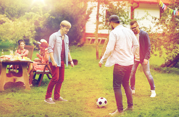 happy friends playing football at summer garden