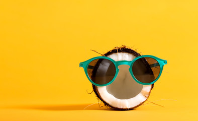 fresh coconut wearing sunglasses on a bright yellow background