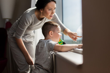 Wall Mural - mother and son looking through window at home