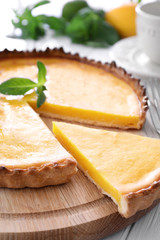 Poster - Wooden plate with delicious lemon pie on table, closeup