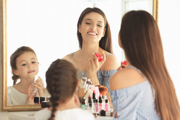 Canvas Print - Young woman and her little daughter applying makeup at home