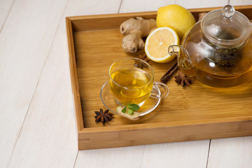 Wall Mural - Cup of ginger tea with lemon and honey on white wooden background.