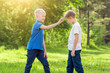 © R - Blond boy click his finger on the forehead of his friend in a sunny park