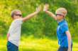 © R - Two blond boys in sunglasses give five their hands in the summer park