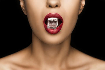 cropped view of seductive woman with red lips holding ice cube in mouth, isolated on black