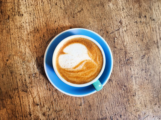 Poster - Coffee cup with heart pattern  in coffee shop on wooden table with vintage style effect, close up with copy space .