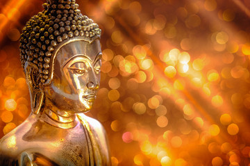 Selective focus of buddha statue with soft lighting effect and glitter abstract background with bokeh defocused lights. Concept of peace, meditation, hope and relaxation