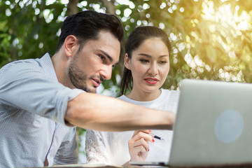 Business man and women working in the garden with laptops.