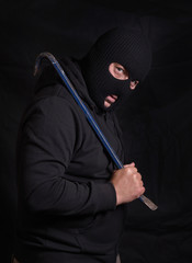 Vertical image of a threatening man with a balaclava mask and holding a crowbar