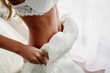 Sexual bride in white lace lingerie is putting on her white wedding dress. Morning preparation