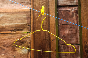 hangover - simple yellow metal hanger on blue roop with wooden background