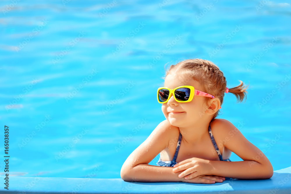 Smiling cute little girl in sunglasses in pool in sunny day. - obrazy, fototapety, plakaty 