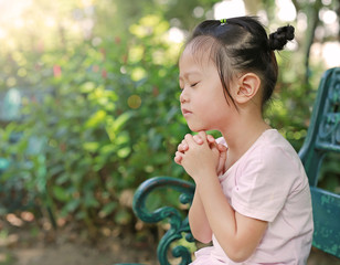 Kid girl praying in the garden.