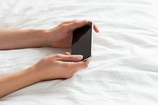 Woman checking the cell phone on the bed