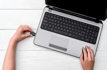 Hand Inserting USB Flash Drive Into Laptop Computer On White Background. Close Up Of Woman Hand Plugging Pendrive On Laptop At Home. Copying Data From Flash Drive To Laptop Computer