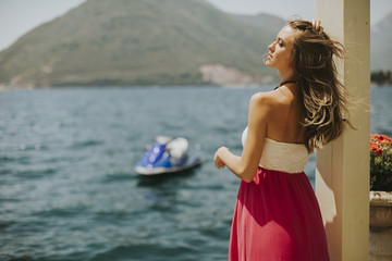 Young attractive woman in a dress relaxing by the sea