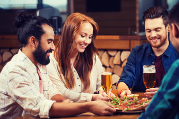 Wall Mural - friends sharing pizza with beer at pizzeria