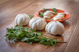 Fototapeta Miasto - White garlic bulb in an orange plate and leaves of green parsley