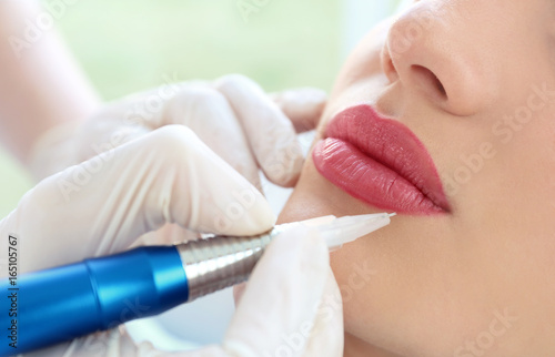 Cuadros en Lienzo Young woman having permanent makeup on lips in beautician salon