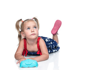 Portrait of a small beautiful girl in a dress lying on the floor and looking up, isolated on a white background