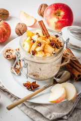 Healthy vegan food. Dietary breakfast or snack. Apple pie overnight oats, with apples, yogurt, cinnamon, spices, walnuts. In a glass, on a white marble table. Copy space