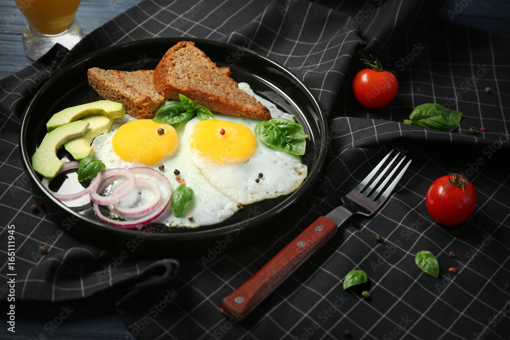 Delicious over easy eggs with toasts, onion and avocado on kitchen table