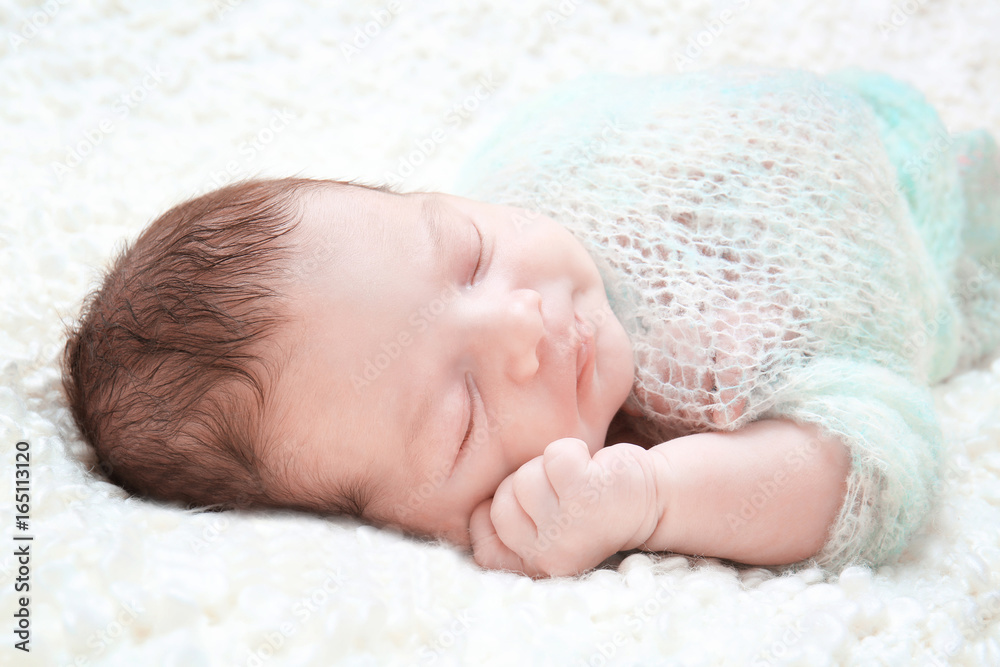 Sleeping newborn baby boy on soft plaid at home
