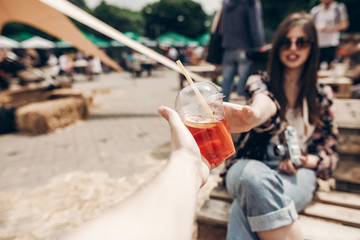 Wall Mural - lemonade in hand. man giving lemonade to stylish hipster woman in sunglasses with red lips. cool boho girl with cocktail at street food festival. summer vacation, space for text