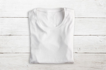 Wall Mural - White folded t-shirt on white wooden texture