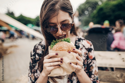 Valokuva stylish hipster woman holding juicy burger and eating