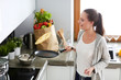 © lenets_tan - Young woman prepares pancakes in the kitchen while standing near the table. Woman in the kitchen. Cooking at kitchen.