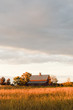 © Deirdre Malfatto/Stocksy - red barn or stable in a field of dry grass in autumn