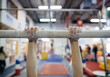 © Stocksy - Child practices on the parallel bars in a gymnastics gym