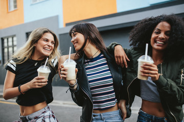 Wall Mural - Female friends with ice coffee on city street