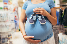 Young Pregnant Woman Checking And Buying Shoes For Her Baby 