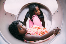 Two African-American Girls Playing In A Playground Slide