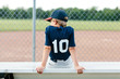 © Kelly Knox/Stocksy - Young baseball player sitting on the bench