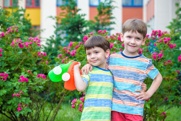 Two little kid boys watering roses with can in garden. Family, garden, gardening, lifestyle