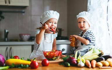 Wall Mural - Healthy eating. Happy children prepares  vegetable salad in kitchen.