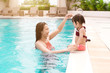 © makistock - Mother and baby girl having fun in the pool. Summer holidays and vacation concept