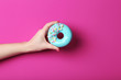 Female hand holding sweet donut with sprinkles