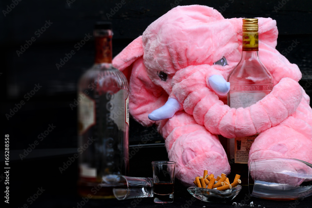 Bottles of alcohol, cigarettes and a pink elephant - the day after a wild  party Stock Photo